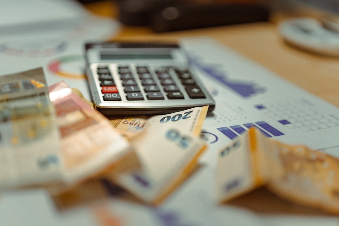 A calculator, Euro banknotes, and financial charts on a desk.