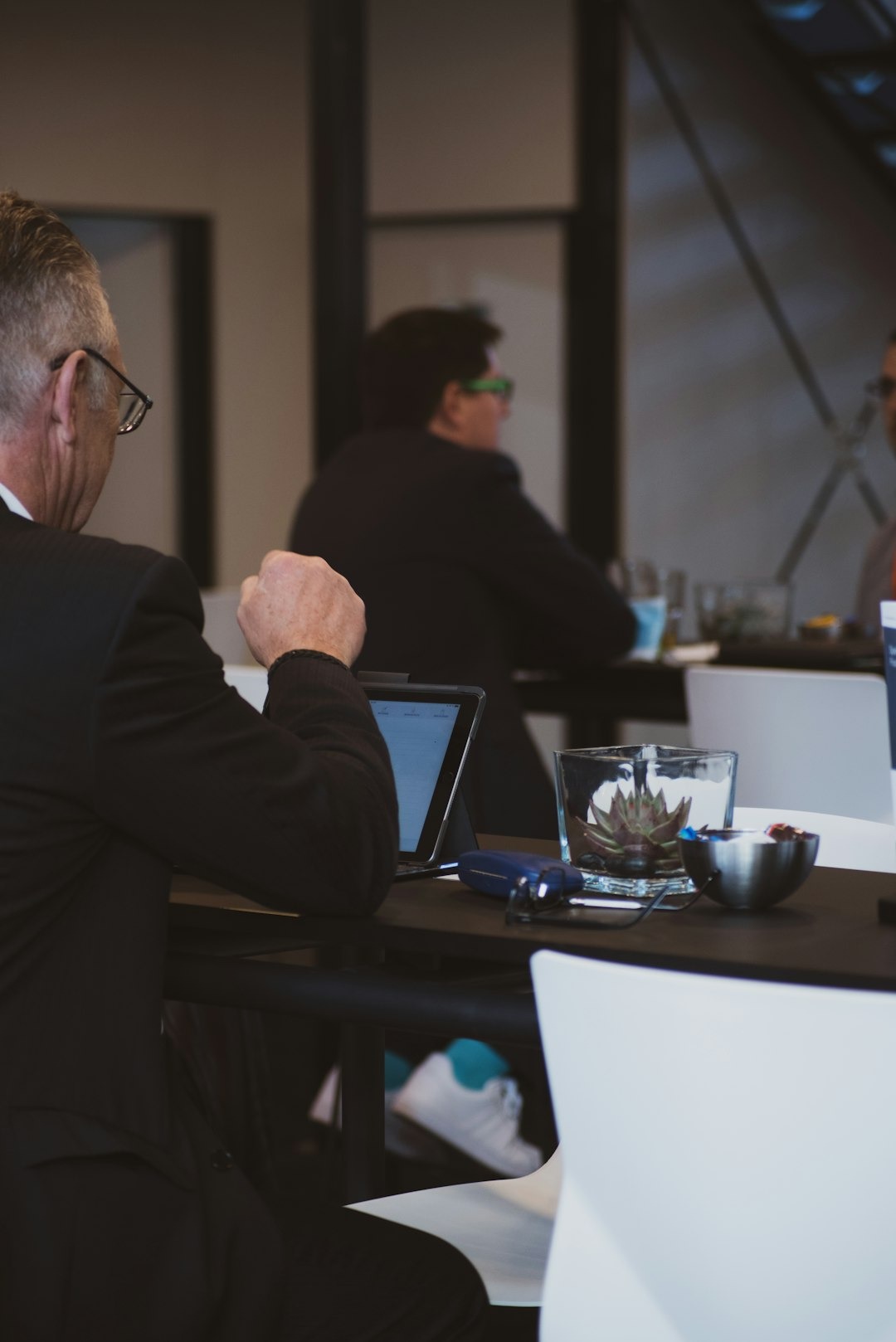 Man in suit looks at tablet at business meeting table.